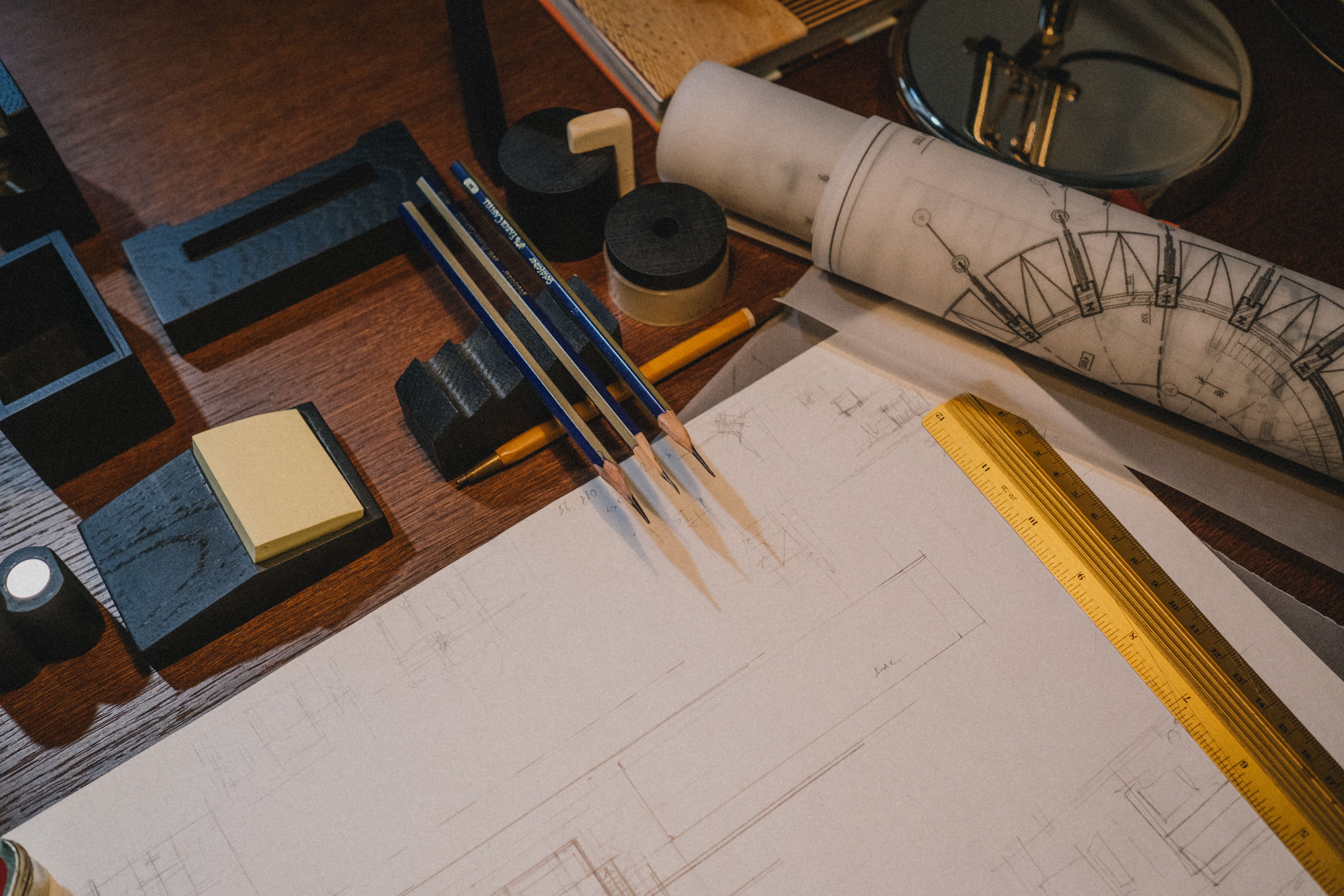 Drafting desk with pencils, ruler, set square and a rolled architectural drawing
